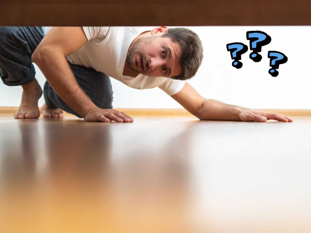 Un homme qui cherche quelque chose sous le lit
