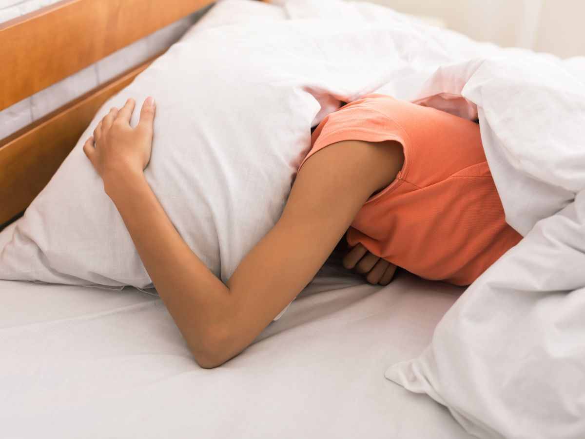 Femme allongée sur le lit avec un oreiller sur la tête