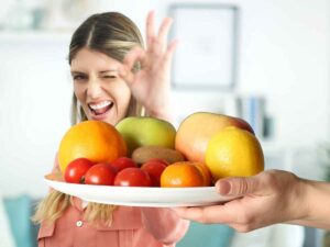 Femme faisant un signe “ok”, au premier plan une assiette de fruits et de légumes