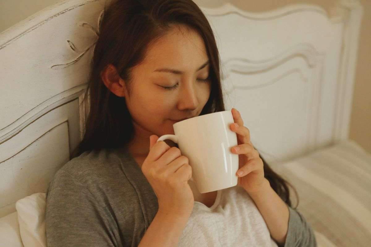 Femme buvant une tisane au lit le soir